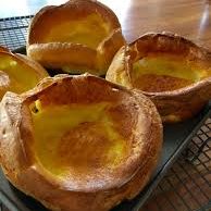 Four golden-brown Yorkshire puddings in a baking tray.